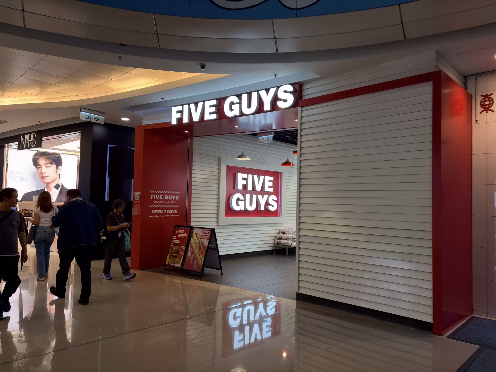 Five Guys 店前,漢堡香氣環繞,疲憊身影流露深夜慰藉的滿足微笑